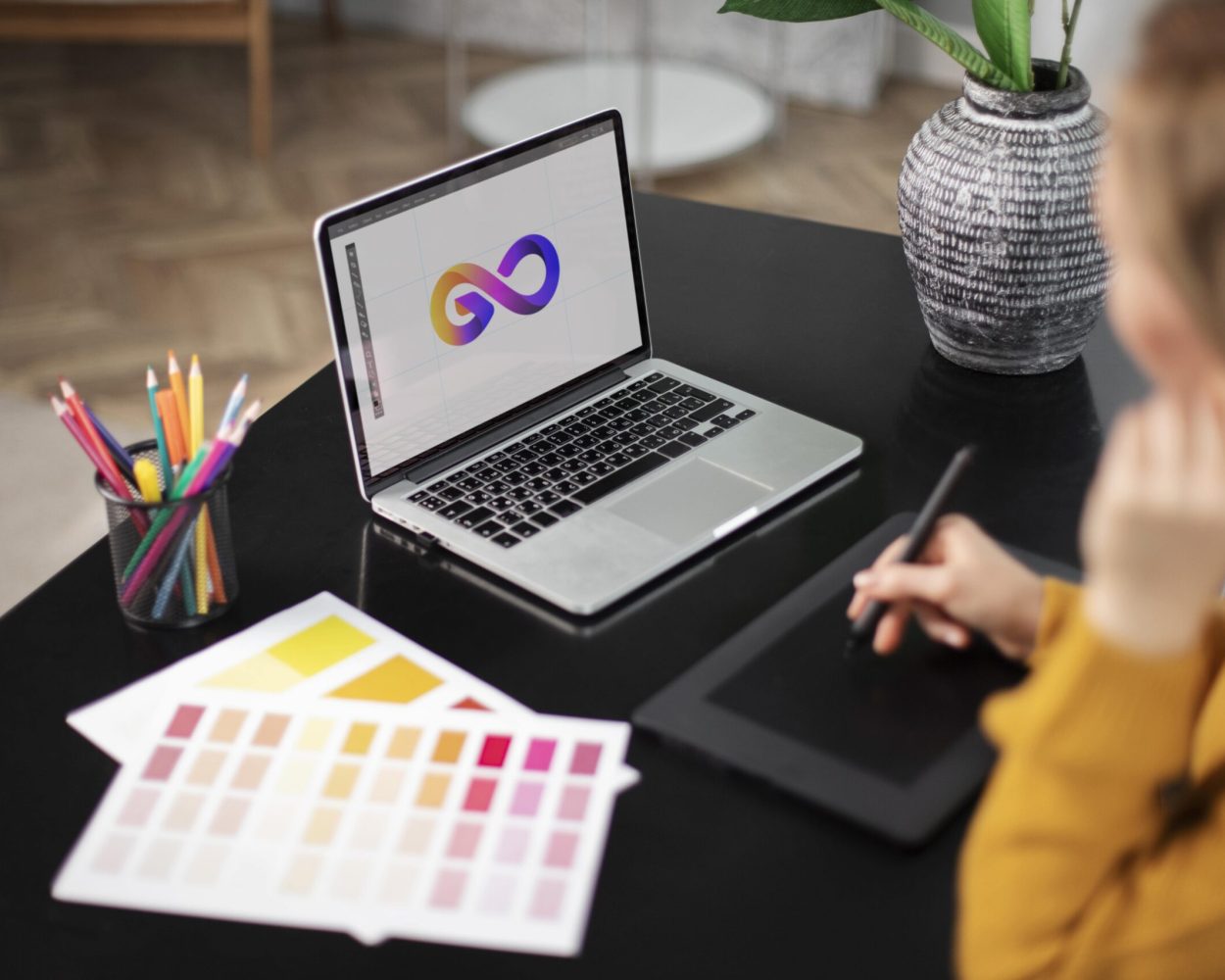 Female logo designer working her tablet connected laptop min